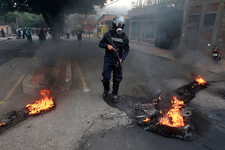 A riot policeman is seen crossing a burned barricade, during a protest against the re-election of Honduras' President Juan Orlando Hernandez in Tegucigalpa, Honduras January 20, 2018. REUTERS/Jorge Cabrera