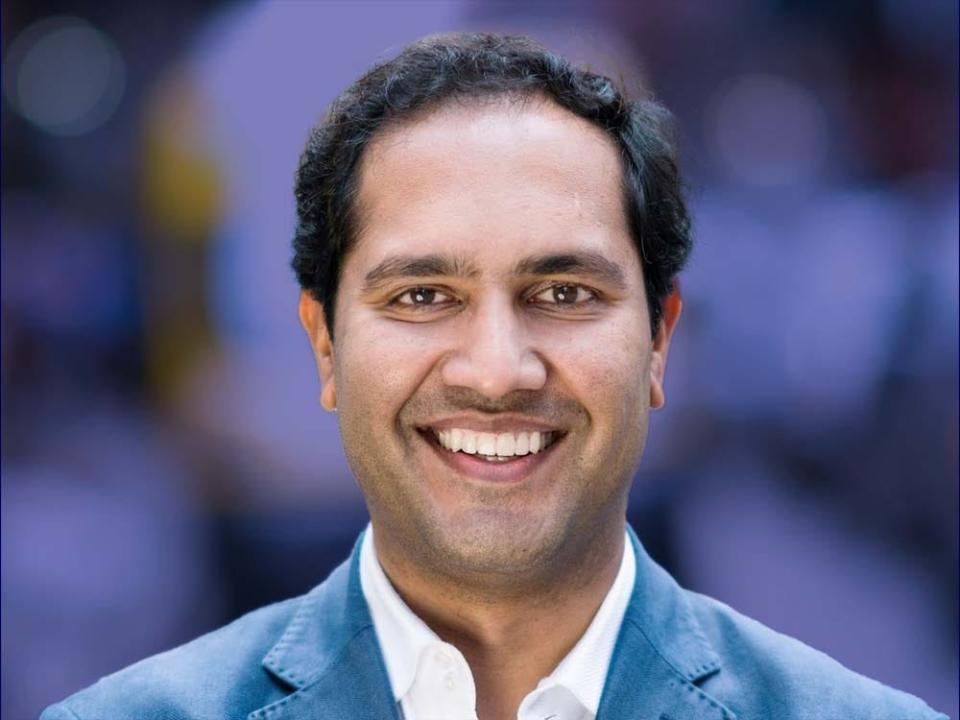 Better CEO Vishal Garg is smiling in a white collared shirt and a blue suit jacket in front of a blurred purple background.