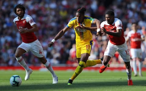 Wilfried Zaha of Crystal Palace takes on Ainsley Maitland-Niles (15) and Mohamed Elneny of Arsenal (4) during the Premier League match between Arsenal FC and Crystal Palace at Emirates Stadium  - Credit: Getty images