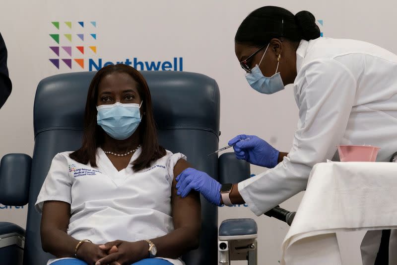 Sandra Lindsay, a nurse at Long Island Jewish Medical Center, is inoculated with the coronavirus disease (COVID-19) vaccine by Dr. Michelle Chester from Northwell Health at Long Island Jewish Medical Center in New Hyde Park, New York