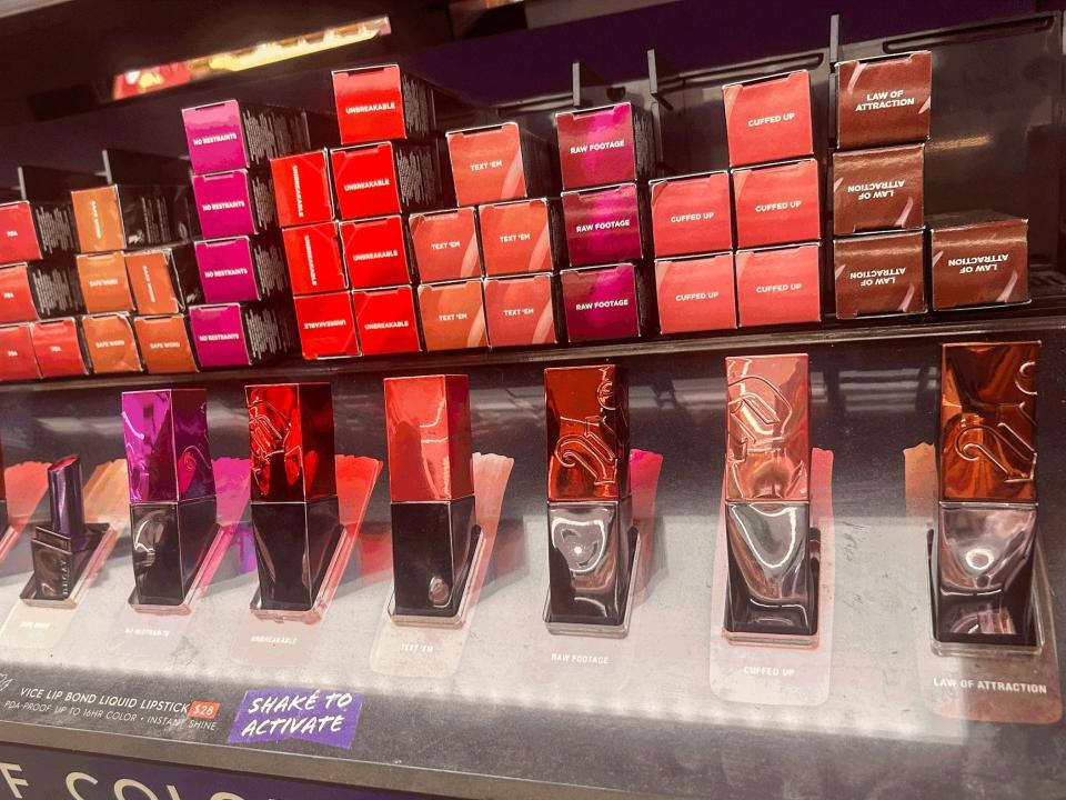 Display of Urban Decay Vice lip bond liquid lipstick. The tubes of lipstick are rectangular shaped and have shiny lids in various shades of pink, red, and brown.