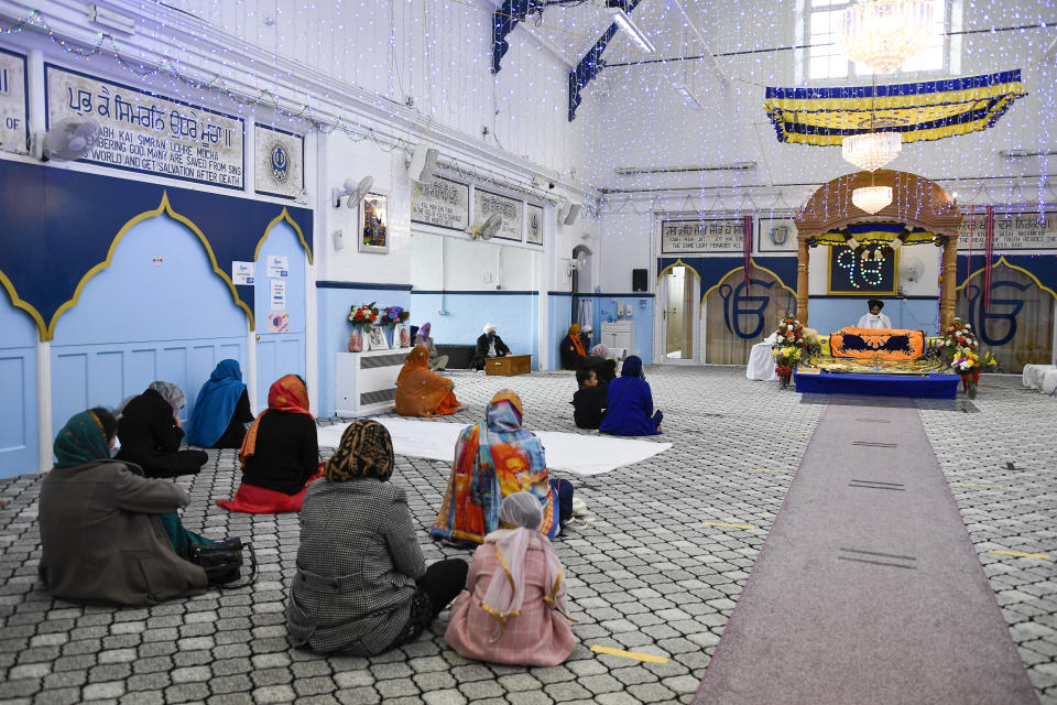 FILE - In this Sunday, March 21, 2021 file photo, people pray at the Guru Nanak Gurdwara Sikh temple, on the day the first Vaisakhi Vaccine Clinic is launched, in Luton, England. Thanks to an efficient vaccine roll out program and high uptake rates, Britain is finally saying goodbye to months of tough lockdown restrictions. From Monday May 17, 2021, all restaurants and bars can fully reopen, as can hotels, cinemas, theatres and museums, and for the first time since March 2020, Britons can hug friends and family and meet up inside other people’s houses. (AP Photo/Alberto Pezzali, File)