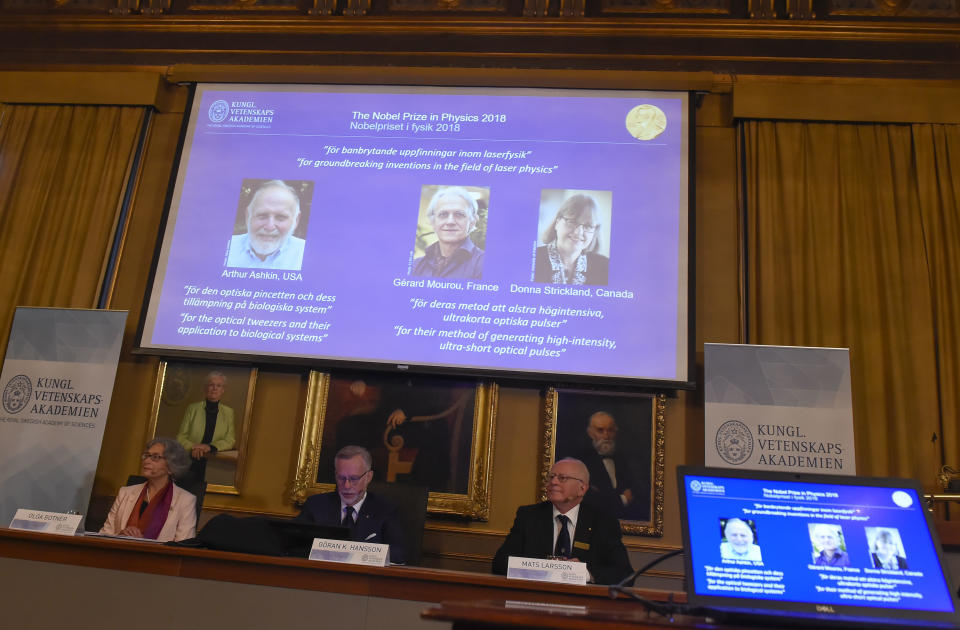 The Nobel Prize laureates for physics 2018 shown on the screen from left, Arthur Ashkin of the United States, Gerard Mourou of France and Donna Strickland of Canada during the announcement at the Royal Swedish Academy of Sciences in Stockholm, Sweden, Tuesday Oct. 2, 2018. The three scientists from the United States, France and Canada have been awarded the Nobel Prize in physics for advances in laser physics. (Hanna Franzen/TT via AP)