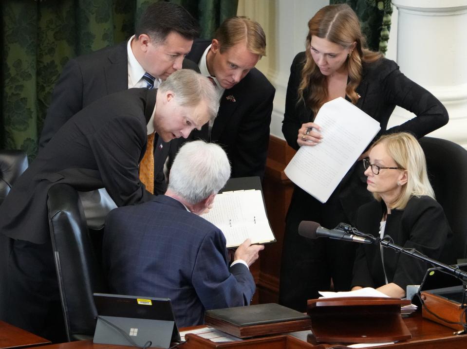 Sen. Brian Birdwell, R-Granbury, left, talks to Lt. Gov. Dan Patrick and his legal counsel, Lana Meyers, Wednesday during Ken Paxton's impeachment trial as they discuss a stack of papers regarding the Paxtons' home improvements.