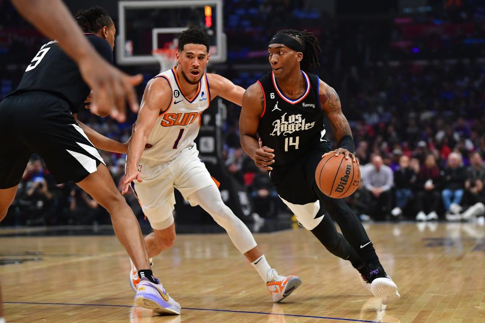 Dec 15, 2022; Los Angeles, California, USA; Los Angeles Clippers guard Terance Mann (14) moves the ball against Phoenix Suns guard Devin Booker (1) during the first half at Crypto.com Arena. Mandatory Credit: Gary A. Vasquez-USA TODAY Sports