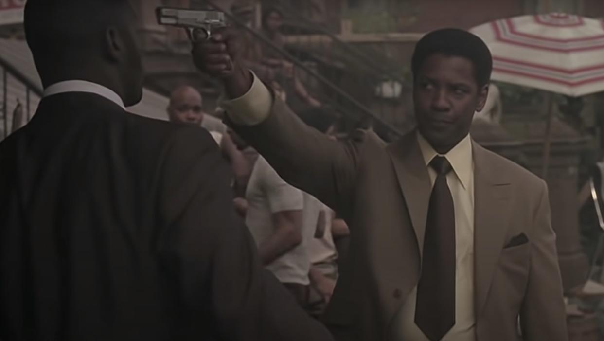 Denzel holds up his gun aimed at Idris