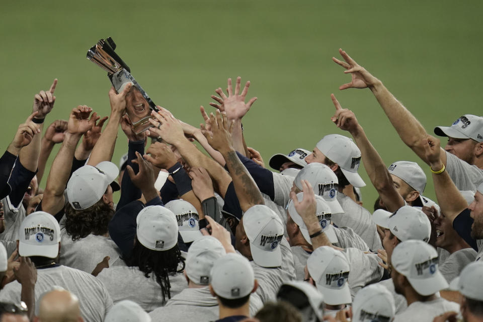 Tampa Bay Rays pitcher Tyler Glasnow is reflected in the American League championship trophy following their victory against the Houston Astros in Game 7 of a baseball American League Championship Series, Saturday, Oct. 17, 2020, in San Diego. The Rays defeated the Astros 4-2 to win the series 4-3 games. (AP Photo/Gregory Bull)