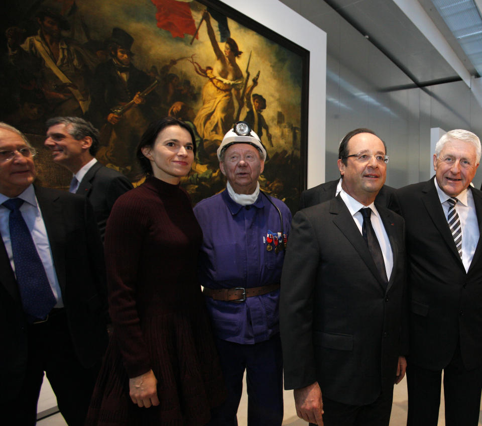 France's President Francois Hollande, second right, is seen with Culture minister Aurelie Filippetti, third left, with a former miner, Lucien Laurent, centre in front of " La Liberte Guidant le Peuple", a painting by Eugene Delacroix during the inauguration of the Louvre Museum in Lens, northern France, Tuesday, Dec. 4, 2012. The museum in Lens is to open on Dec. 12, as part of a strategy to spread art beyond the traditional bastions of culture in Paris to new audiences in the provinces. (AP Photo/Michel Spingler Pool)