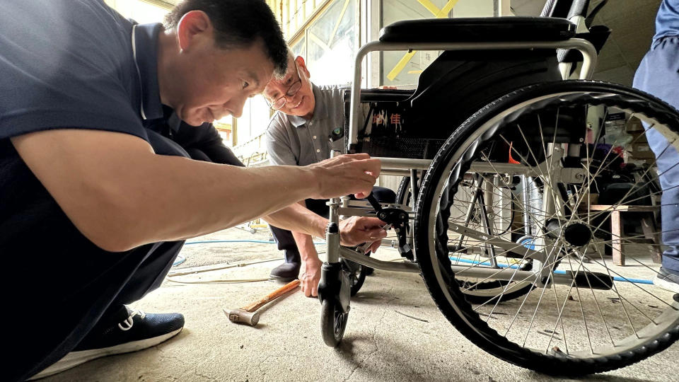 林永軒(左一)專注的仔細檢查輪椅的每一個環節是否正常運轉。