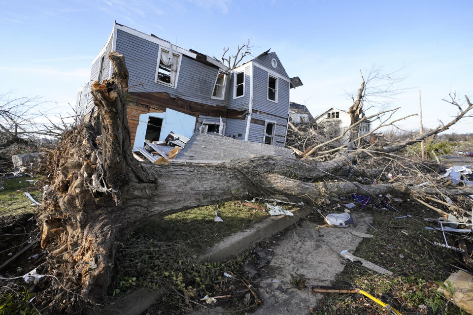 FILE - An overturned tree sits in front of a tornado damaged home in Mayfield, Ky., on Dec. 11, 2021. On Friday, March 17, 2023, The Associated Press reported on stories circulating online incorrectly claiming climate, weather or meteorological events that we would classify as “extreme” have declined in severity over the last 20 or 30 years. (AP Photo/Mark Humphrey, File)