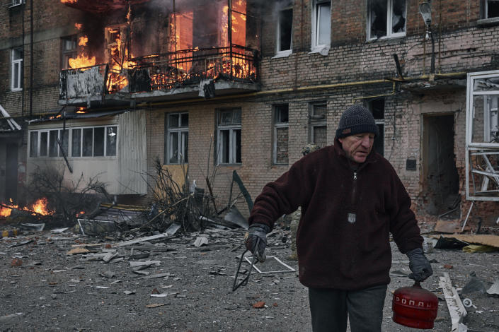 A local resident leaves his home after Russian shelling destroyed an apartment house in Bakhmut, Donetsk region, Ukraine, Wednesday, Dec. 7, 2022. (AP Photo/LIBKOS)