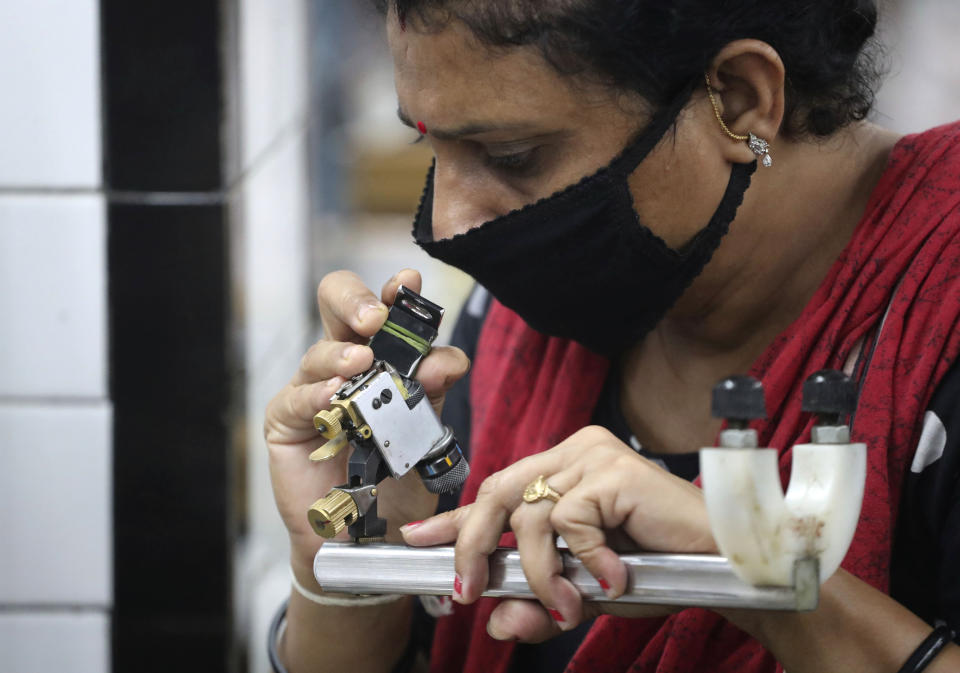 An Indian worker wearing a face mask works at a diamond unit in Ahmedabad, India, Saturday, July 4, 2020. The diamond industry has been hit by the coronavirus outbreak as the main diamond polishing units in Surat city were ordered to remain shut for a week starting June 30 after more than 500 workers and their relatives tested positive for the infection in a month. (AP Photo/Ajit Solanki)