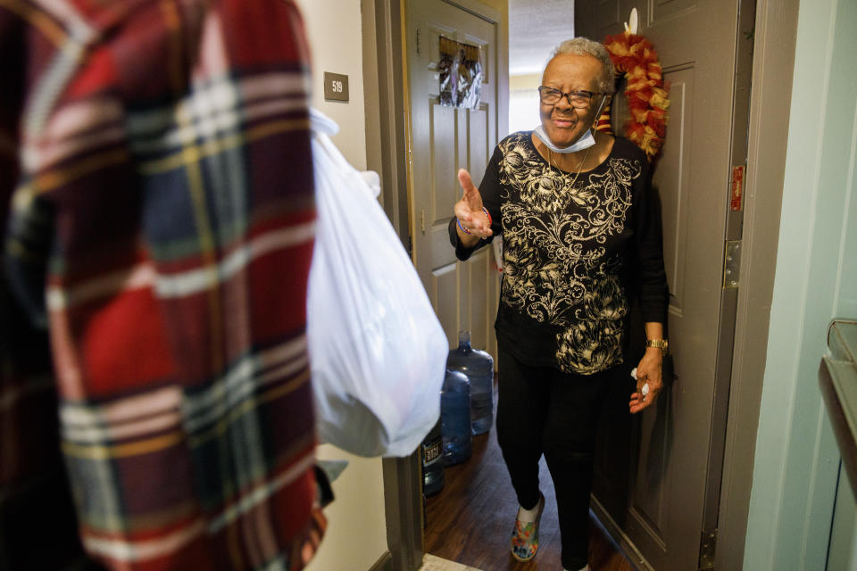 Easter Brown, 77, of Washington, greets Michael Weber, with the nonprofit organization "We Are Family DC," as he delivers groceries to her apartment door, Saturday, March 21, 2020, in Washington. Seniors are being encouraged to stay in their homes due to the risk of the COVID-19 coronavirus. (AP Photo/Jacquelyn Martin)