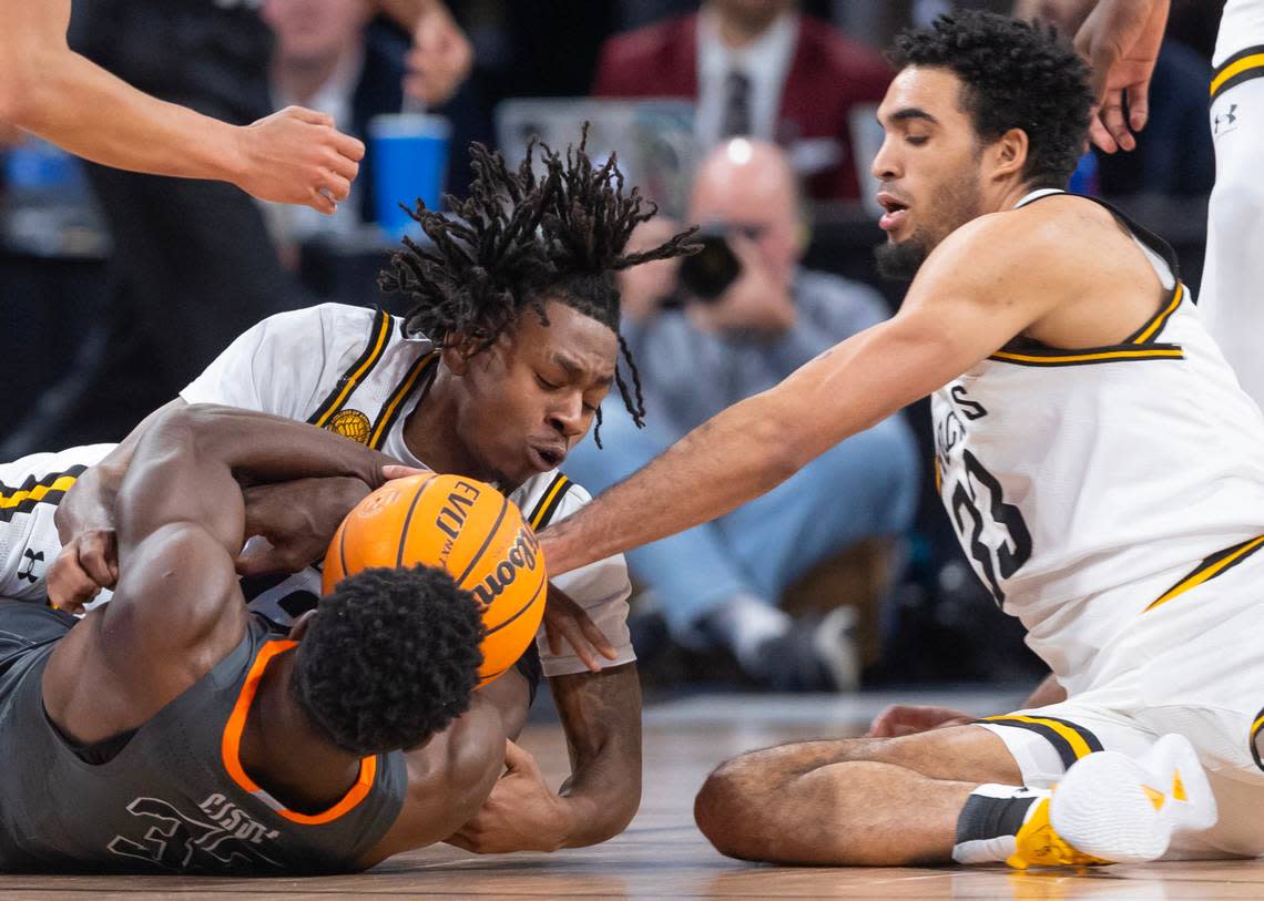 Wichita State’s Melvion Flanagan, left, and James Rojas, right, fight for a loose ball against Oklahoma State’s Moussa Cisse during the second half of their game at Intrust Bank Arena on Saturday night.