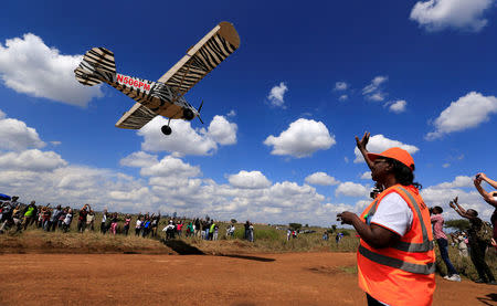 An aviation official and spectators wave as a plane flies over them during the Vintage Air Rally at the Nairobi national park in Kenya's capital Nairobi, November 27, 2016. REUTERS/Thomas Mukoya