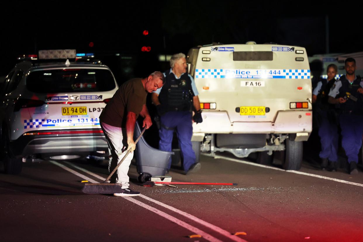 Broken glass is cleaned up from the road after police held back an angry mob following a stabbing at Christ The Good Shepherd Church in the suburb of Wakeley in Sydney (EPA)
