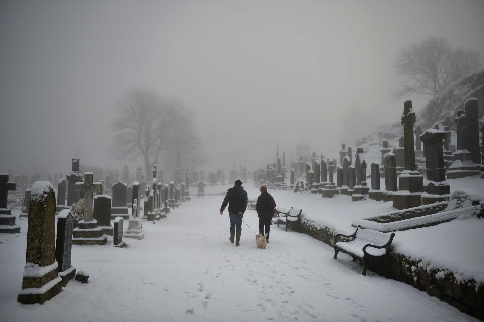 STIRLING, UNITED KINGDOM - DECEMBER 03: A man and woman walk their dog in Stirling Castle graveyard on December 3, 2012 in Stirling, Scotland.Snow and sleet has hit many parts of Scotland with heavier falls expected over higher grounds. (Photo by Jeff J Mitchell/Getty Images)