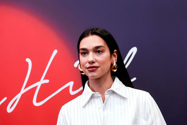 dua lipa poses in white shirt at red carpet event