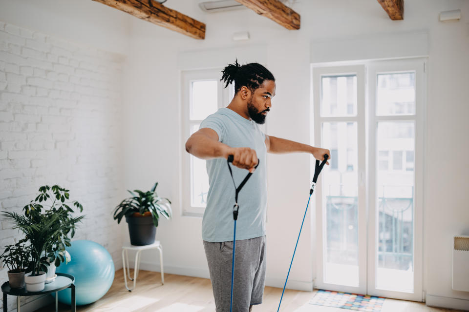 Man doing exercises with resistance bands at home.