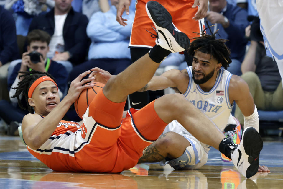 Syracuse forward Benny Williams, left, and North Carolina guard RJ Davis, right, try to get control of a loose ball during the first half of an NCAA college basketball game Saturday, Jan. 13, 2024, in Chapel Hill, N.C. (AP Photo/Chris Seward)