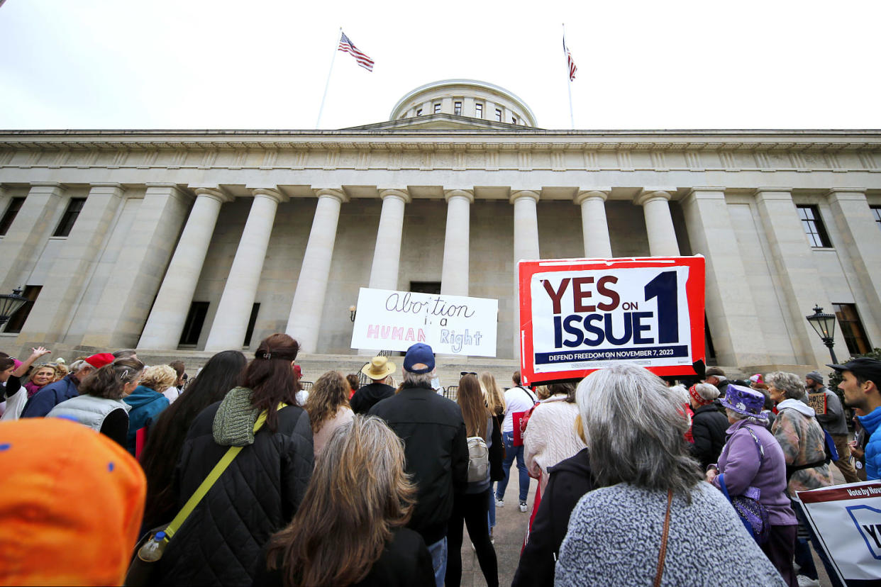 People hold signs and protest in front of the Ohio State House. (Joe Maiorana / AP file)