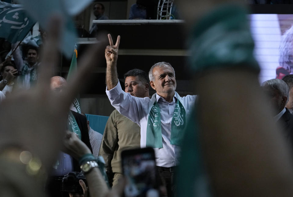 Iranian presidential candidate Masoud Pezeshkian and his supporters flash the victory sign during a campaign stop in Tehran, Iran, Sunday, June 23, 2024. (AP Photo/Vahid Salemi)