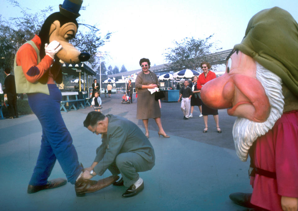 A Disneyland guest ties Goofy's shoes during a visit in 1962.&nbsp;