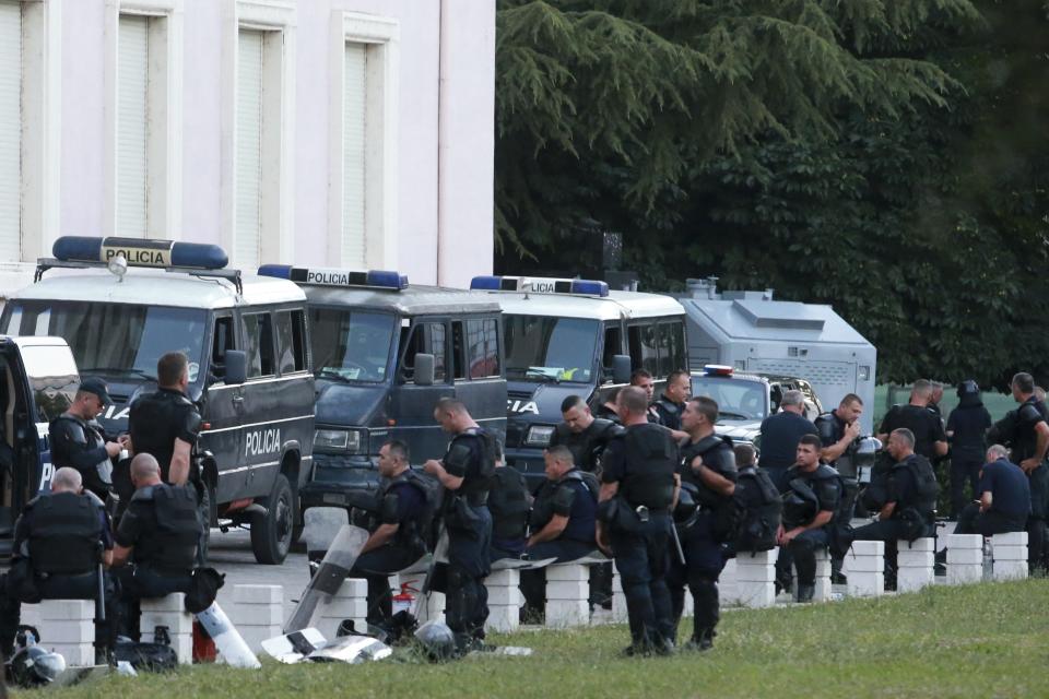Riot police sit outside the office of Albania's Prime Minister Edi Rama during an antigovernment rally in Tirana, Friday, June 21, 2019. The opposition is boycotting the local elections planned for June 30 and has threatened to disrupt them.(AP Photo/Hektor Pustina)