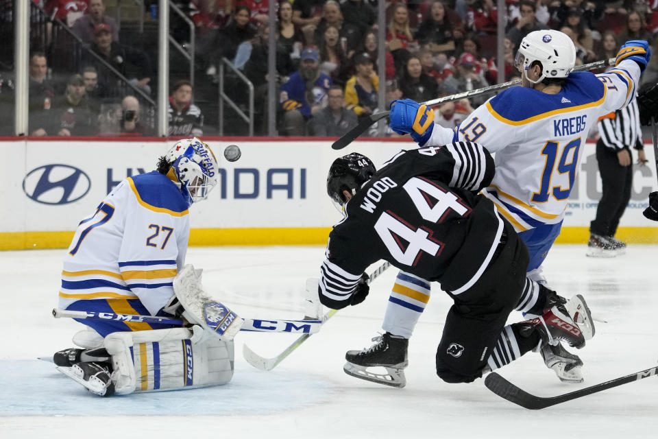 Buffalo Sabres goaltender Devon Levi (27) makes a save against New Jersey Devils left wing Miles Wood (44) during the second period of an NHL hockey game, Tuesday, April 11, 2023, in Newark, N.J. (AP Photo/John Minchillo)