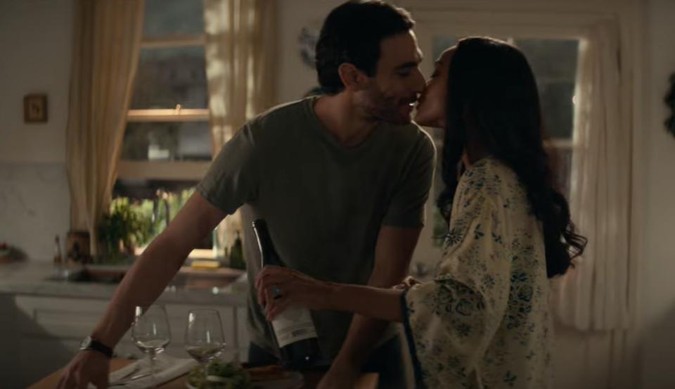In a scene from the Netflix series 'From Scratch' Lino and Amy kiss in the kitchen as he cooks and she holds a bottle of wine