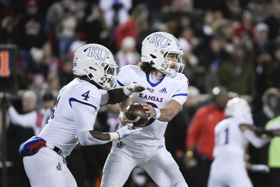 Kansas quarterback Jason Bean hands off to running back Devin Neal (4) during the first half of the team's NCAA college football game against Texas Tech on Saturday, Nov. 12, 2022, in Lubbock, Texas. (AP Photo/Justin Rex)