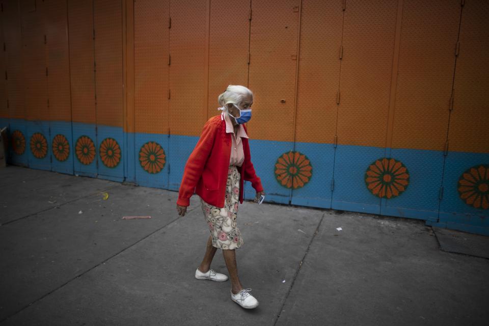 An elderly woman wearing a protective face mask walks on a street in Caracas, Venezuela, Friday, July 17, 2020, amid the new coronavirus pandemic. (AP Photo/Ariana Cubillos)