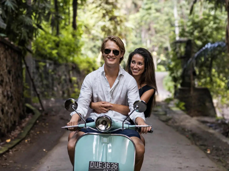 Ein Paar fährt auf einem Roller durch Bali. - Copyright: Martin Puddy/Getty Images