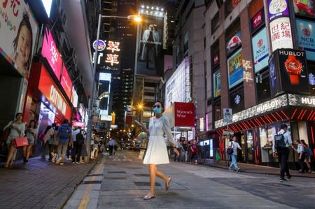 FILE PHOTO: A woman crosses a street in the Central business district in Hong Kong, China