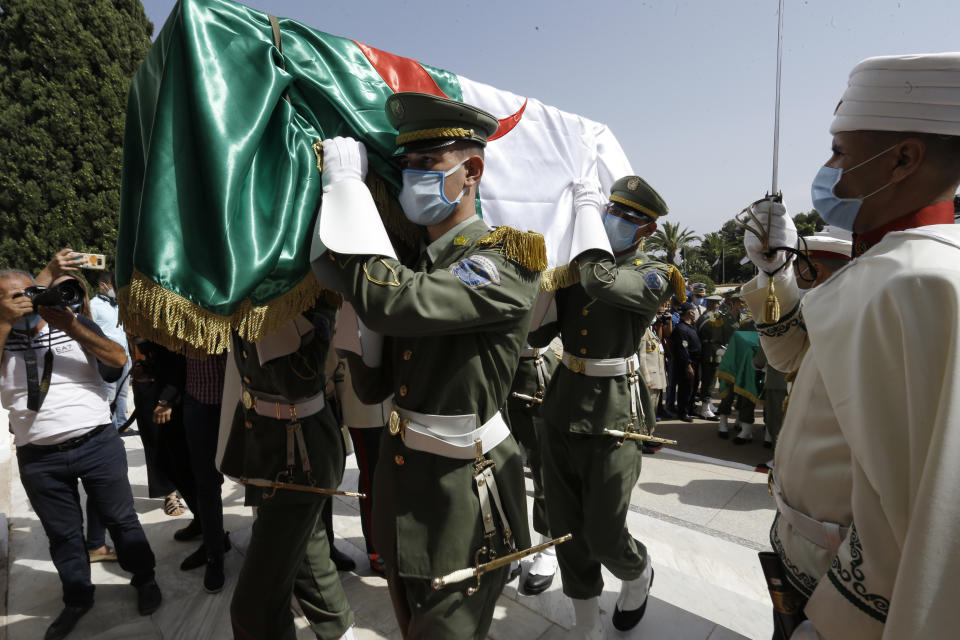 The remains of 24 Algerians are carried by members of the Algerian Republican Guard at the Moufdi-Zakaria culture palace in Algiers, Friday, July, 3, 2020. After decades in a French museum, the skulls of 24 Algerians decapitated for resisting French colonial forces were formally repatriated to Algeria in an elaborate ceremony led by the teary-eyed Algerian president. The return of the skulls was the result of years of efforts by Algerian historians, and comes amid a growing global reckoning with the legacy of colonialism. (AP Photo/Toufik Doudou)