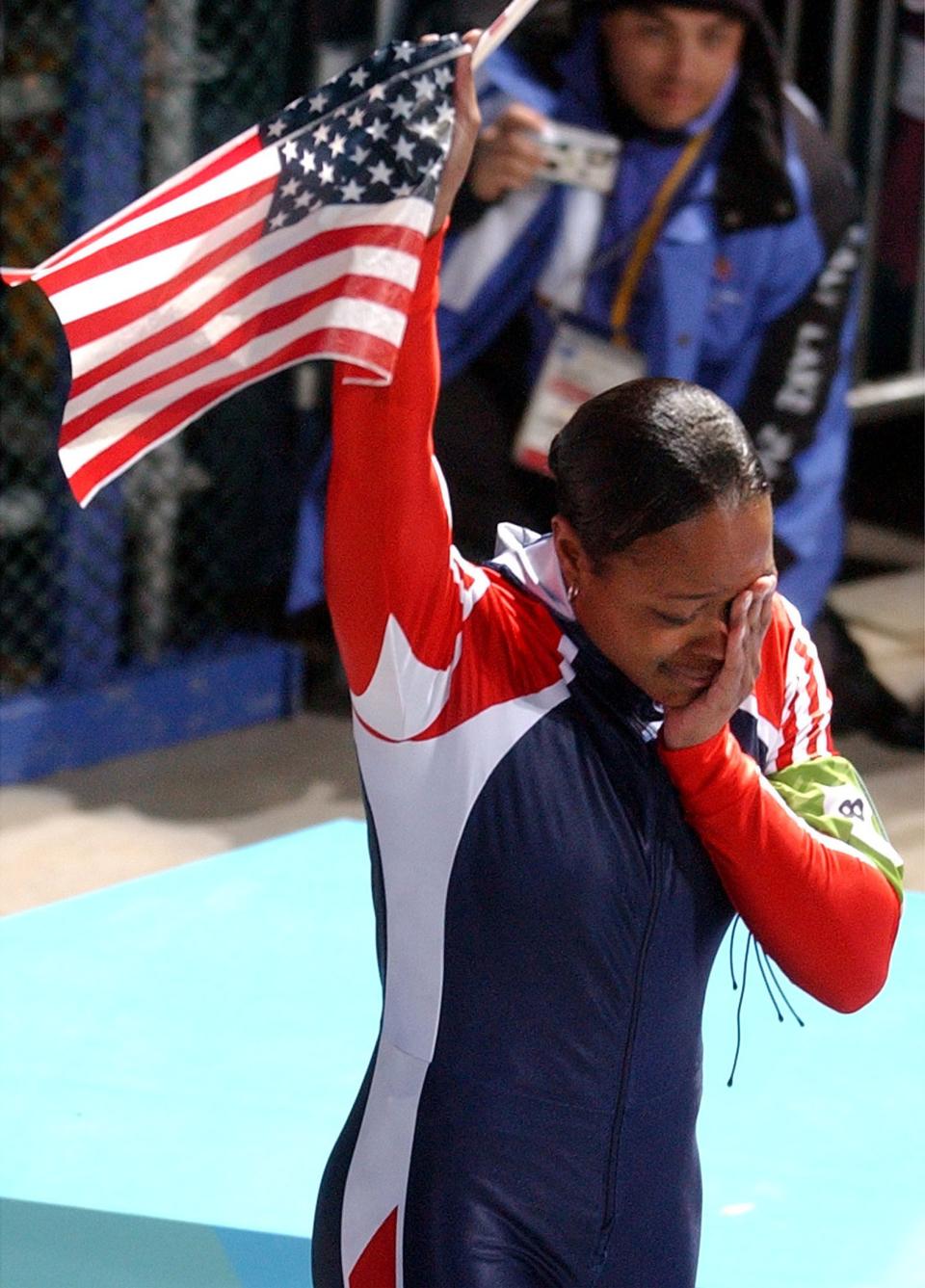 USA’s Vonetta Flowers, brakeman to Jill Bakken, wipes tears from her face and waives an American flag after her and Bakken won the gold medal in the women’s bobsled at the Utah Olympic Park on Tuesday, Feb. 19, 2002. | Johanna Kirk, Deseret News