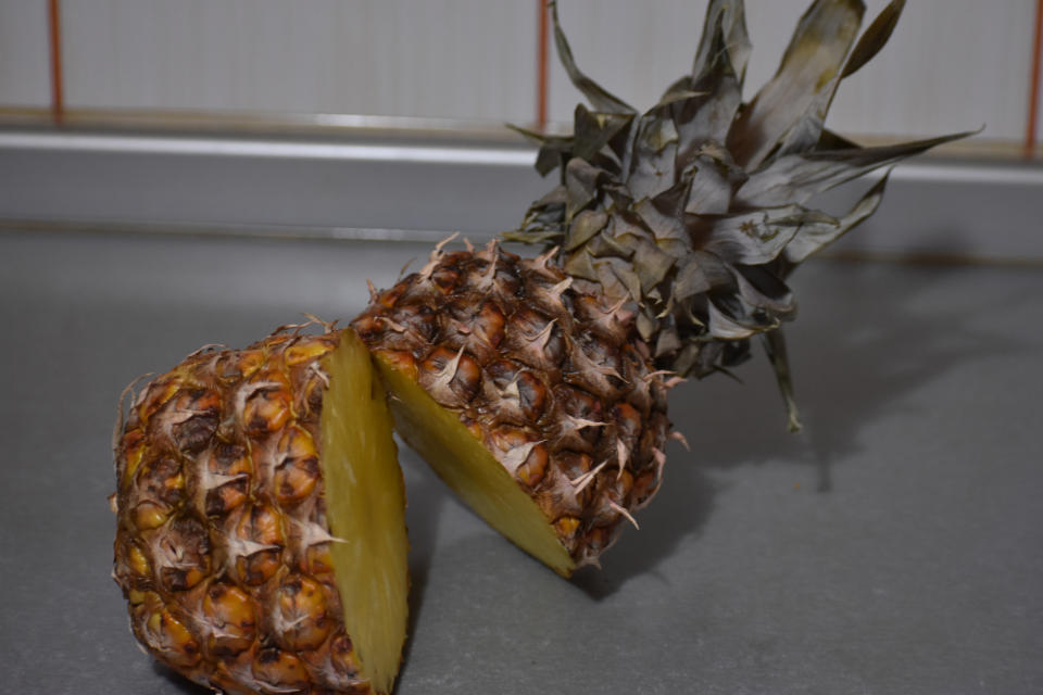 Sliced pineapple with top and bottom parts on a kitchen counter