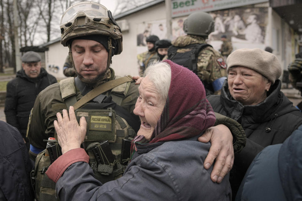 A woman hugs a Ukrainian serviceman after a convoy of military and aid vehicles arrived in the formerly Russian-occupied Kyiv suburb of Bucha, Ukraine, Saturday, April 2, 2022. As Russian forces pull back from Ukraine's capital region, retreating troops are creating a "catastrophic" situation for civilians by leaving mines around homes, abandoned equipment and "even the bodies of those killed," President Volodymyr Zelenskyy warned Saturday.(AP Photo/Vadim Ghirda)