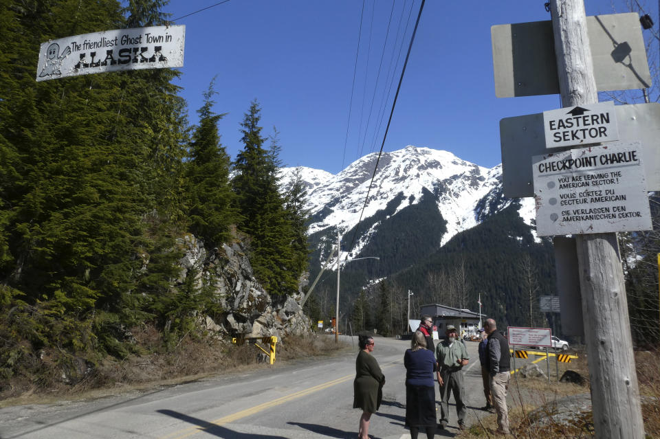 These signs are at the edge of Hyder, Alaska, with a Canada Border Services Agency site in the background on Thursday, April 22, 2021, in Hyder, Alaska. Alaska Gov. Mike Dunleavy said Alaska is in a fortunate position with its vaccine supply and wants to share vaccines with people across the border in Stewart, British Columbia, a community that has close ties to Hyder. (AP Photo/Becky Bohrer)