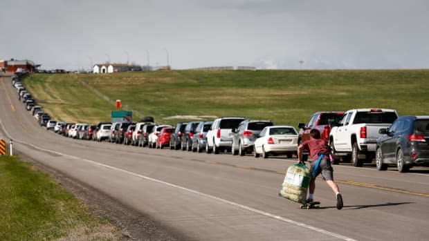 A enterprising teenager selling popcorn skateboards up and down the lineup of Canadians waiting at the Carway border crossing on May 18, 2021.