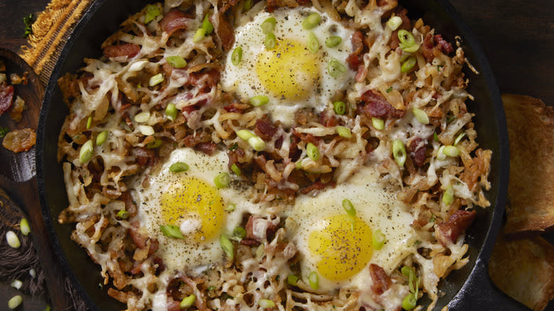 hash browns in pan with eggs