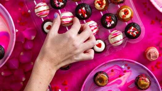 a pink table covered in pink and red colorful cupcakes