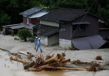 Men walk in front of damaged houses surrounded by swept away after heavy rain in Asakura, Fukuoka Prefecture, Japan July 9, 2017. REUTERS/Issei Kato