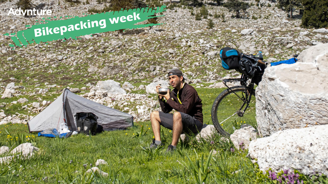  Bikepacker eating food outside tent 