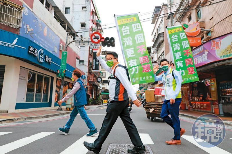 民進黨許多公職祭奇招宣傳公投，新北綠委吳秉叡（中）就率子弟兵翁震州（右）背工字旗徒步掃街。