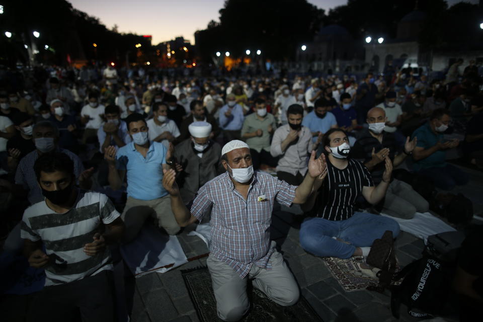 Muslims offer their evening prayers outside the Byzantine-era Hagia Sophia, one of Istanbul's main tourist attractions in the historic Sultanahmet district of Istanbul, following Turkey's Council of State's decision, Friday, July 10, 2020. Turkey's highest administrative court issued a ruling Friday that paves the way for the government to convert Hagia Sophia - a former cathedral-turned-mosque that now serves as a museum - back into a Muslim house of worship. The Council of State threw its weight behind a petition brought by a religious group and annulled a 1934 cabinet decision that changed the 6th century building into a museum. (AP Photo/Emrah Gurel)