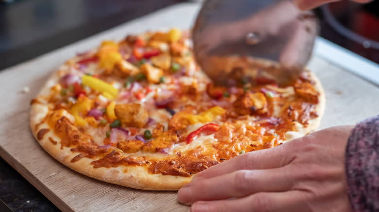 slicing a cooked frozen pizza