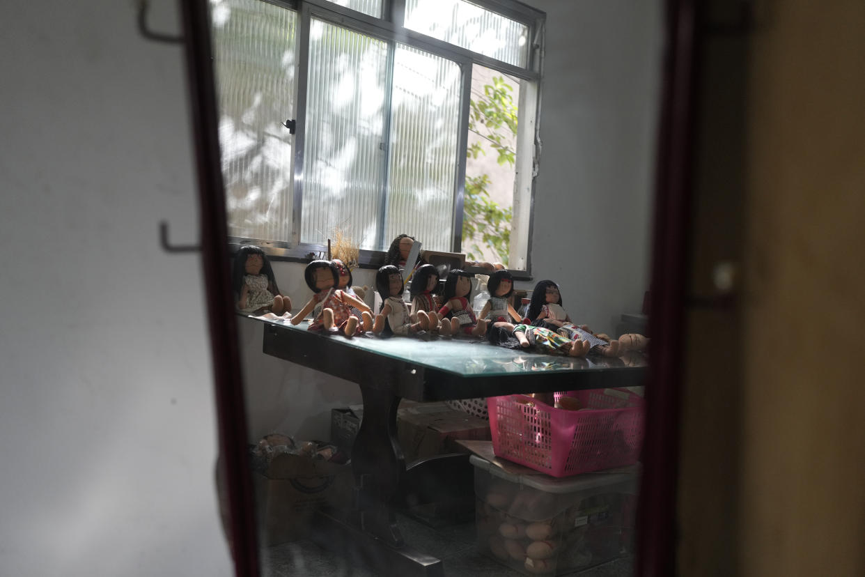 Dolls bearing faces and body paints of different Indigenous groups are displayed on a table at a sewing workshop in Rio de Janeiro, Brazil, Tuesday, May 24, 2022. Each one of them is hand sown, dressed in clothes created by Luakam Anambe, of Brazil’s Anambe Indigenous group, and carefully painted by her daughter Atyna Pora. (AP Photo/Silvia Izquierdo)