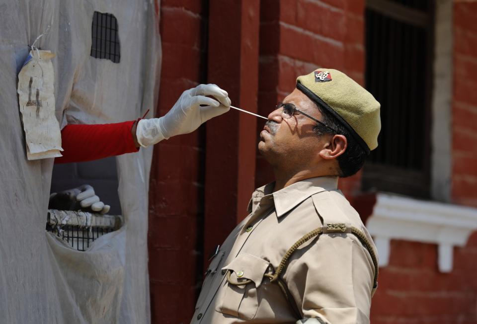 A health worker takes a nasal swab sample from a uniformed officer