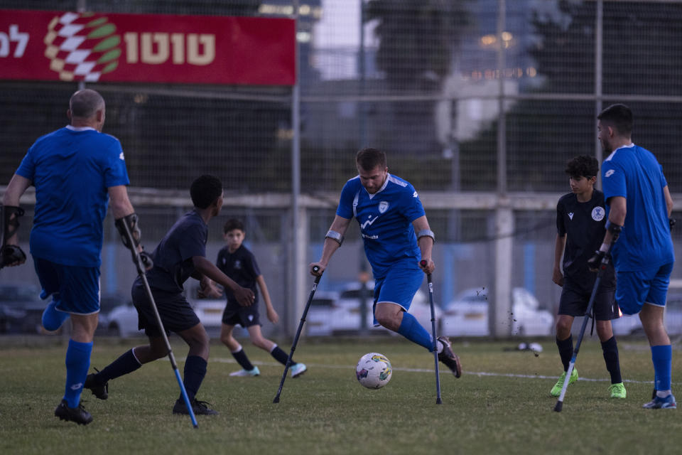 Israel Amputee Football Team player, Ben Binyamin, center, prepares to kick the ball during practice session in Ramat Gan, Thursday, April 11, 2024. During the Oct. 7 attack by Hamas militants at the Tribe of Nova music festival, Binyamin, 29, raced into an air raid shelter, but attackers fired shots and then threw in grenades. He was seriously wounded; his right leg was blown off. He was left for dead. (AP Photo/Leo Correa)